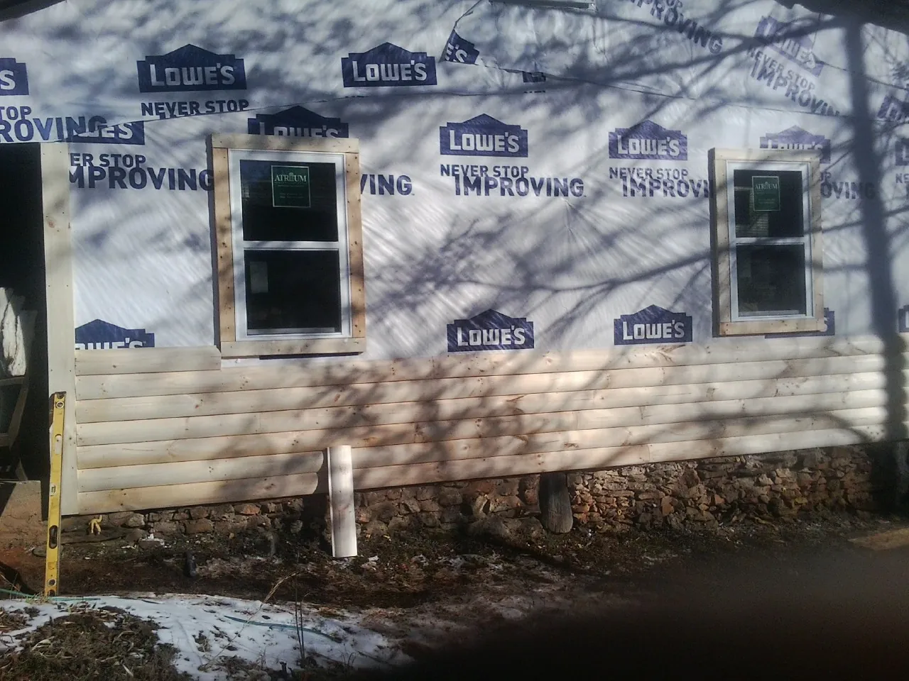 House wrap and new log siding going up on an exterior wall in West End