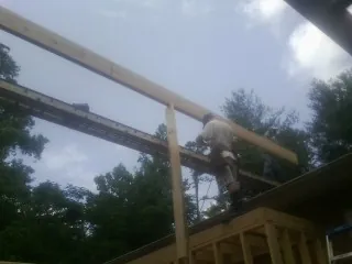 Carpenter setting a ridge beam over a new addition frame — Ice Dam Removal by Roofing Brothers in West End