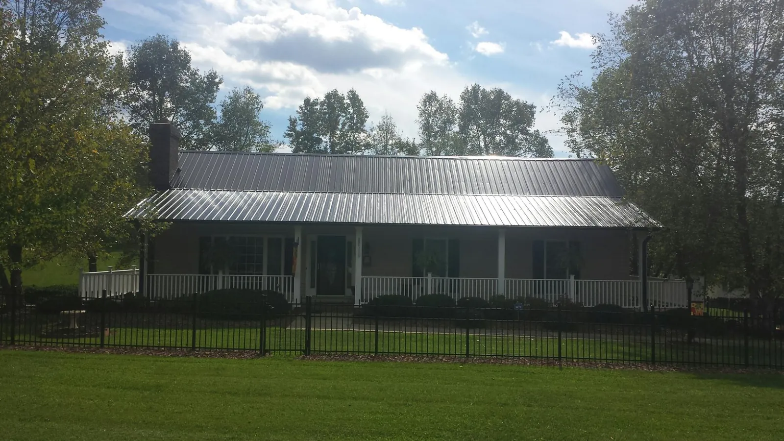 Gray metal roof on a brick ranch with a full width front porch — Gutter Guard Installation work by our crew in West End