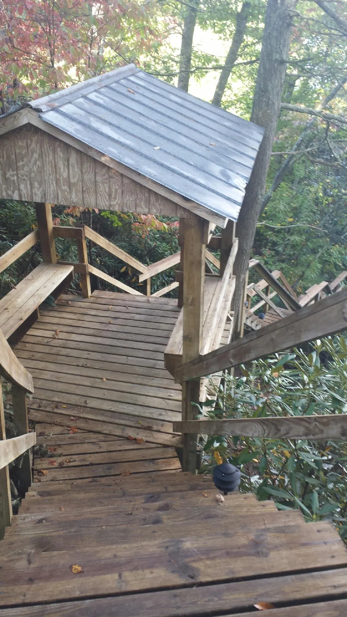 Metal roofed shelter over wooden steps on a wooded walkway — Skylight Repair & Installation work by our crew in West End