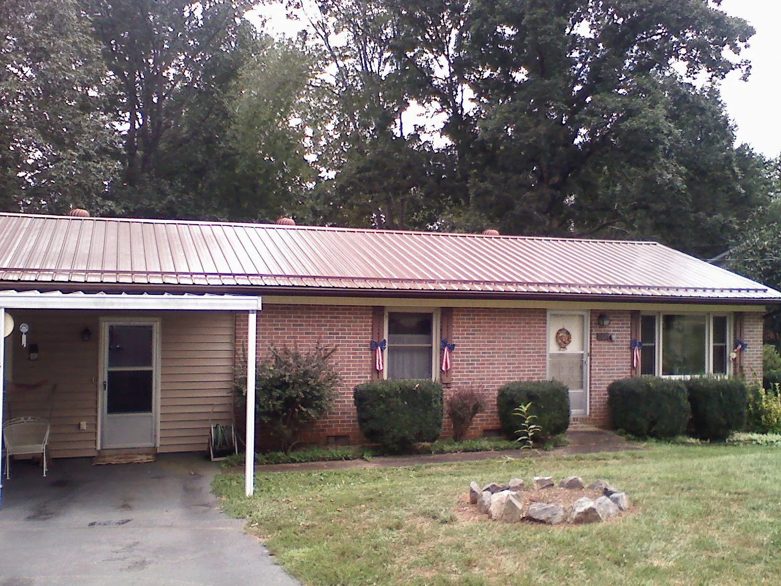 Bronze metal roof and carport on a brick ranch home — Roof Repair work by our crew in West End